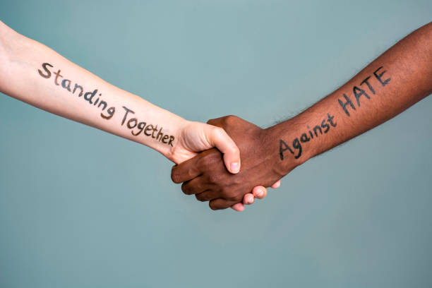 Handshake between black and white human woman and male hands with the message text Standing Together against HATE. Handshake between black and white human woman and male hands with the message text Standing Together against HATE. Concept of protest protest against racism and police brutality. peace demonstration photos stock pictures, royalty-free photos & images