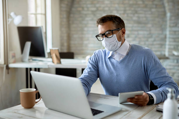 istock Businessman wearing protective face mask while working in the office. 1248616897