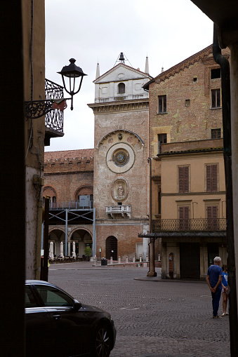 Bell tower with astronomic clock next to the Ragione palace, seen from the distance, in Mantova, Italy