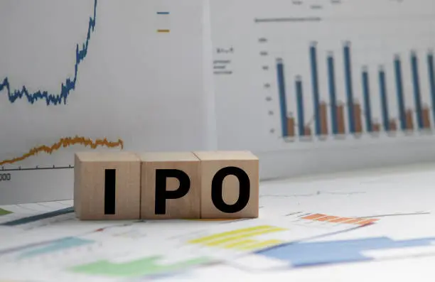 Photo of A Notebook with Business notes initial coin offering ICO vs IPO Initial Public Offering with office tools on yellow blue background. Concept of the choice of IPO or ICO