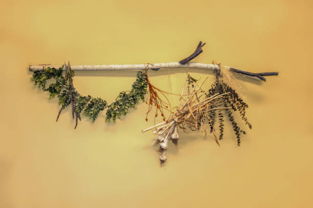 istock Rustic decorative wall hanging of branch with dried greenery and garlic attached against a yellow wall 1248630633