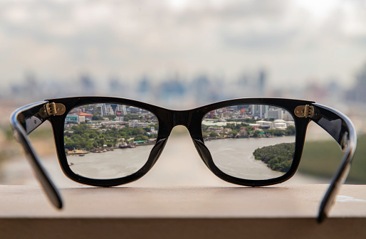 Black eyeglass on a reflective surface. View through the lens of glasses that look at the Chao Phraya River.