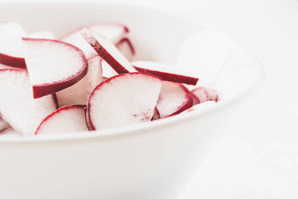 Sliced radish in a white bowl on white background
