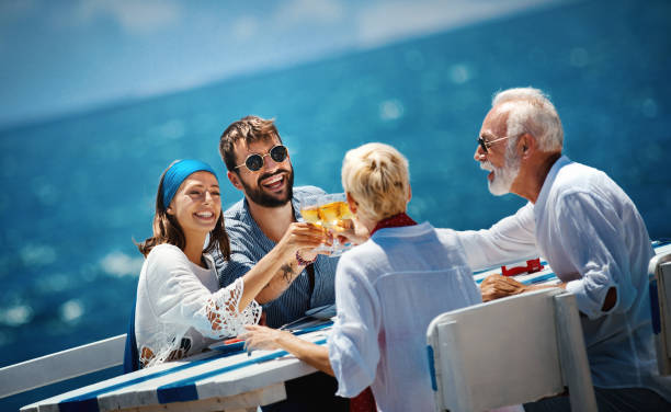 Family on a sailing cruise. Closeup side view of a senior couple having lunch with their son and his fiancee while sailing during their summer vacation. cruise ship photos stock pictures, royalty-free photos & images