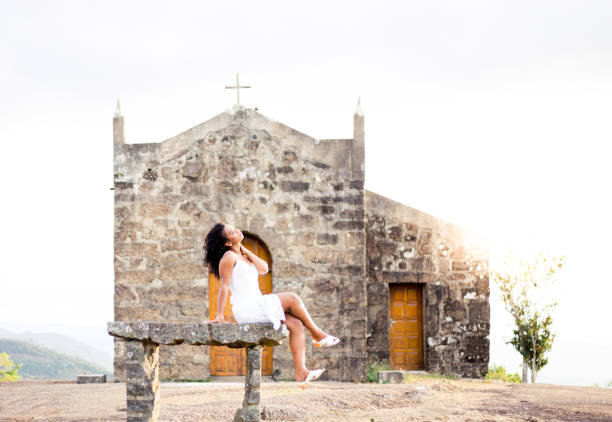 Beautiful black woman sitting with an old church in the background