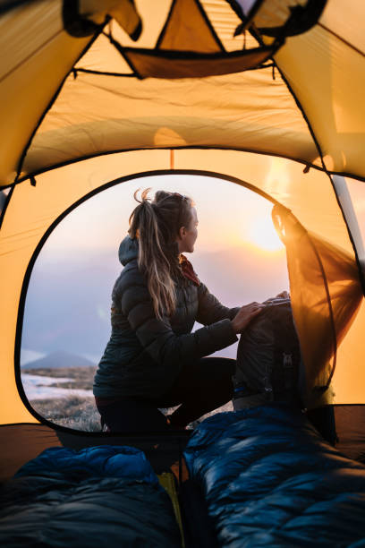 młoda kobieta ogląda wschód słońca z namiotu kempingowego - hairstyle crest zdjęcia i obrazy z banku zdjęć
