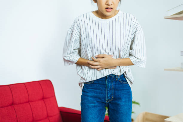 young woman having painful stomach ache,women suffering from abdominal pain,period cramps,stomach pain - colic imagens e fotografias de stock