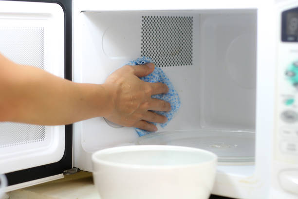 Clean a microwave oven Using a cloth to clean a microwave oven in kitchen room inside microwave stock pictures, royalty-free photos & images