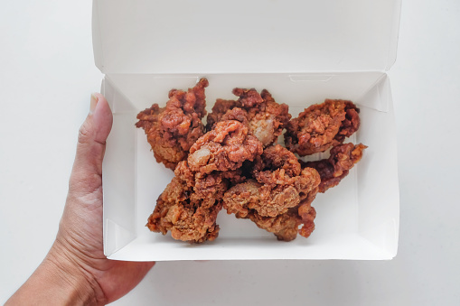 Close up shot of Asian woman holding her takeout meal box with crunchy chicken karaage on the inside
