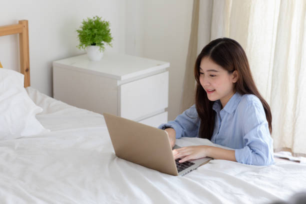 istock Cute asian girl freelancer lying on the bed working on a laptop, having breakfast in bed. Work from home, stay home concept, home office, working home, self-isolation. 1248653725