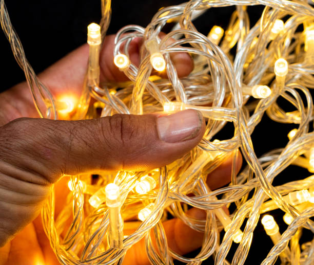 istock Led string lights with Asian hand holding them on black background, Yellow in colour. 1248654995