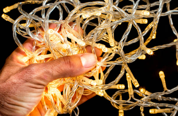 istock Led string lights with Asian hand holding them on black background, Yellow in colour. 1248654996