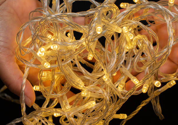 istock Led string lights with Asian hand holding them on black background, Yellow in colour. 1248654997