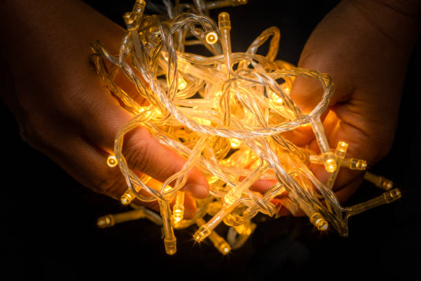 istock Led string lights with Asian hand holding them on black background, Yellow in colour. 1248655004