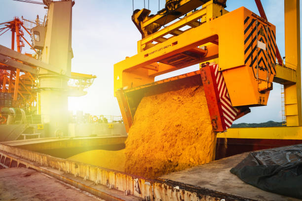 Raw sugar bulk loaded into large vessel hole by rotainer for export. Sugar bulk products transport and handling. Agro-industry concept.
