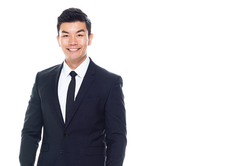 One person of aged 20-29 years old east asian ethnicity young male businessman standing in front of white background who is smiling