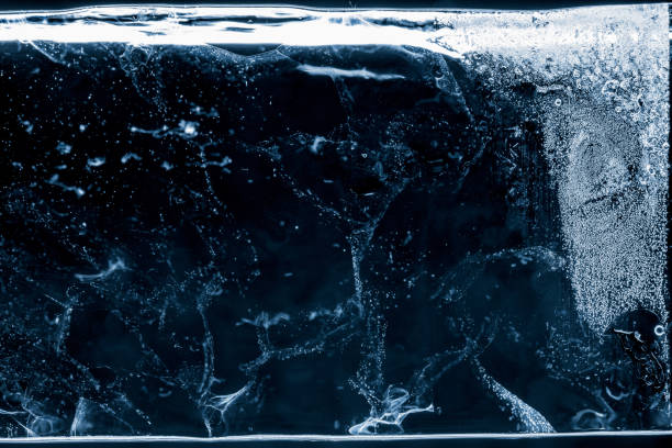 Ice texture blue toned background. Textured frosty surface of thick ice block with air bubbles on black background.