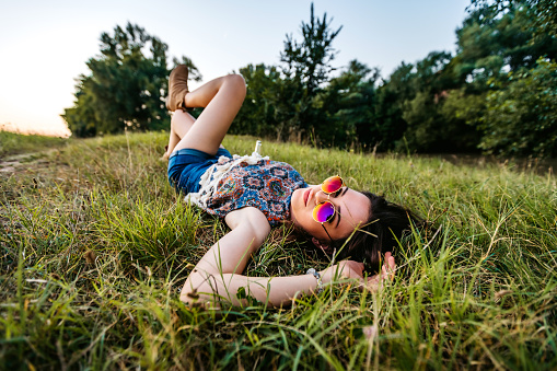 Young caucasian beautiful woman lying on grass with drink.