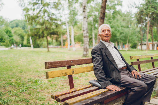 istock Senior man sitting on a park bench 1248661690
