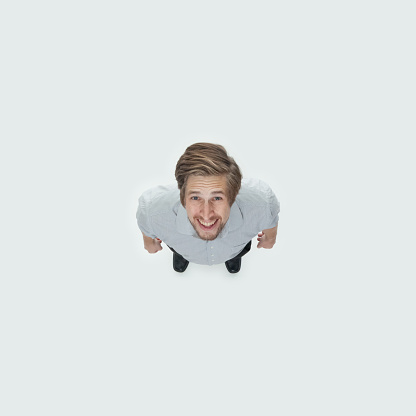 Directly above view of aged 20-29 years old with brown hair caucasian young male standing in front of white background wearing button down shirt who is excited with hand by side