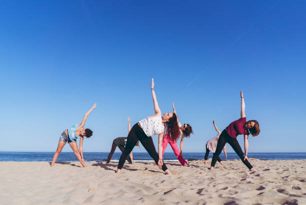 group yoga on the beach - stretch beach imagens e fotografias de stock