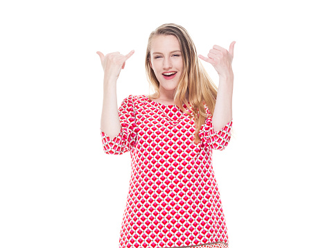 One person of aged 18-19 years old who is beautiful caucasian teenage girls standing in front of white background wearing dress who is showing cool attitude who is show shaka sign ( hang loose )