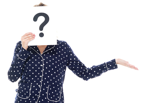Waist up of aged 20-29 years old who is beautiful with blond hair caucasian female standing in front of white background wearing nightwear who is confused and showing question mark