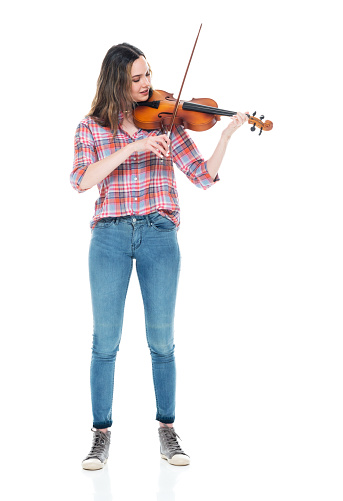 One person of aged 20-29 years old who is beautiful caucasian female violinist standing in front of white background wearing pants who is showing cool attitude and holding violin