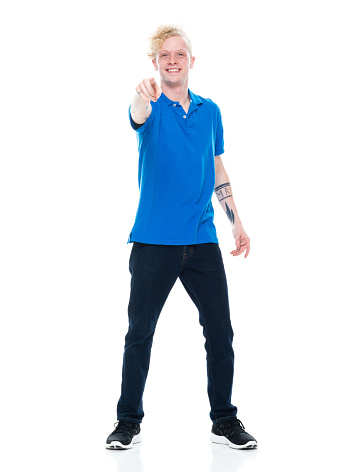 Front view of aged 20-29 years old with blond hair caucasian male standing in front of white background wearing polo shirt who is laughing who is pointing