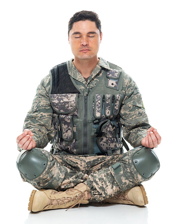 Front view of aged 30-39 years old who is tall person with black hair caucasian male armed forces meditating in front of white background in the military wearing uniform who is cross-legged and showing patriotism