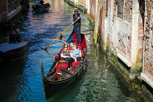 Venice, Italy - 04 08 2017: Tourists are sightseeing Venice canals in gondola boat, Italy. Venice is one of the most important tourist destinations in the world for its celebrated art and architecture.