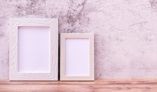 Two Picture frame on wall background and wooden table. Poster product design styled