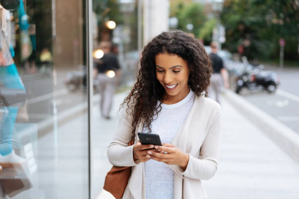 istock Happy young woman using her smartphone in town 1248676357