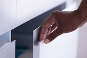 Opening / closing cabinet door. Female's hand holding drawer door aluminum handle.