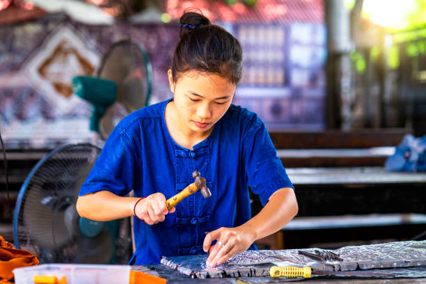 istock Asian woman making silverware. Thai Craftsman are making silverware. The original of the silver craftsmen on Wua Lai road, Chiang Mai. Thailand. 1248679231