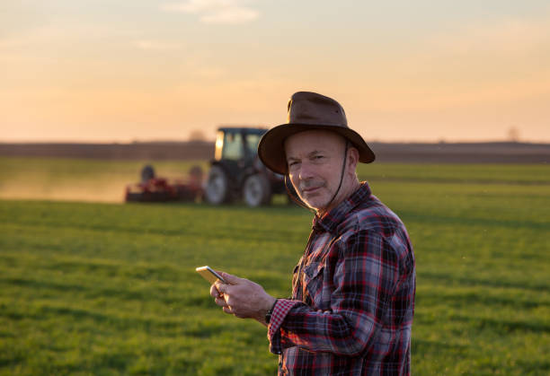 istock Farmer with tablet in field and tractor in background 1248681592
