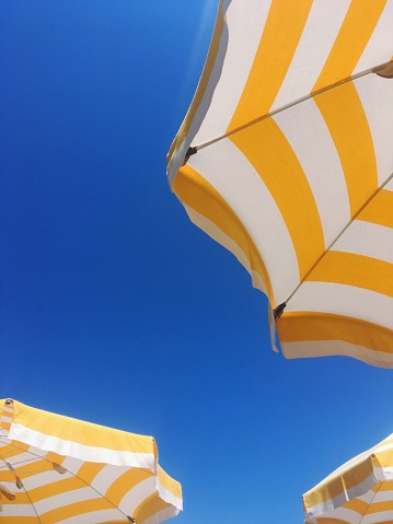 Holiday and vacation concept detail of white and yellow parasols with a blue sky
