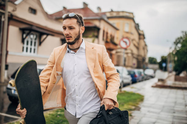 istock Modern man with skateboard running to work on rainy day 1248685138