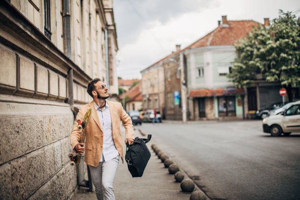 istock Businessman with skateboard running on sidewalk on rainy day 1248686461