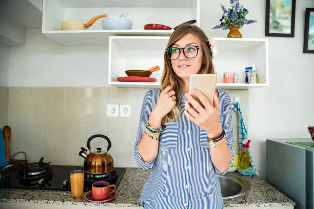 istock Modern young woman using cellphone in the kitchen. 1248686594