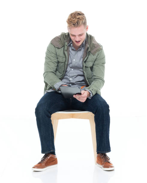 istock Caucasian boys resting in front of white background wearing jeans and using digital tablet 1248686633