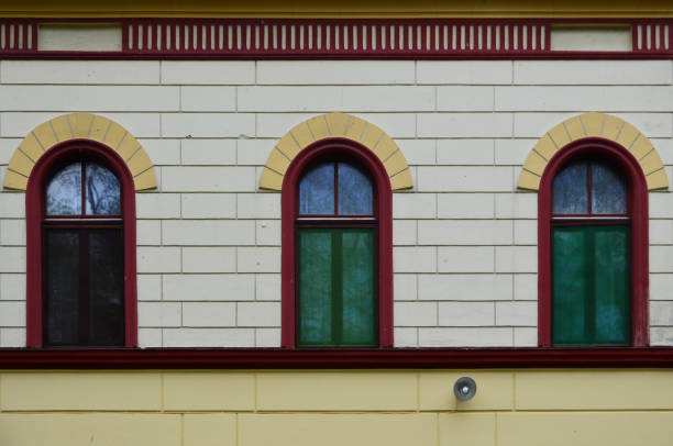 istock Three windows on the white and yellow  bricks wall and lamp on it 1248687462