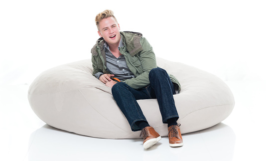 One person of aged 18-19 years old caucasian teenage boys in front of white background wearing shirt who is laughing