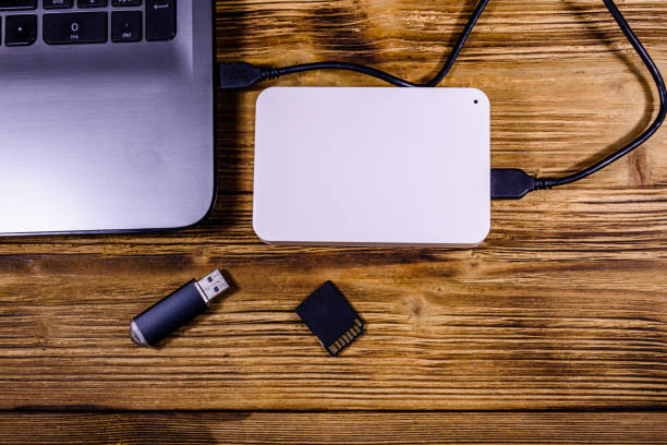 現代のラップトップ、sdカード、フラッシュメモリカード、木製デスクのssdハードドライブ - external hdd ストックフォトと画像