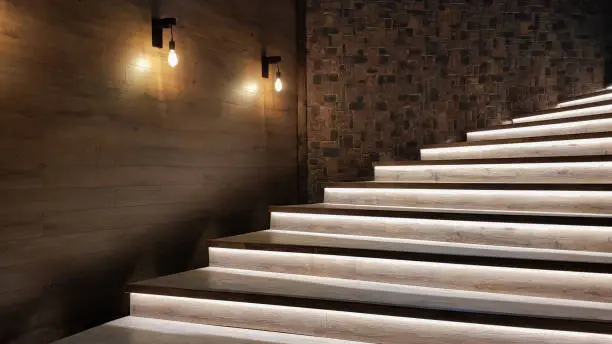 Photo of Illuminated staircase with wooden steps and illuminated at night in the interior of a large house