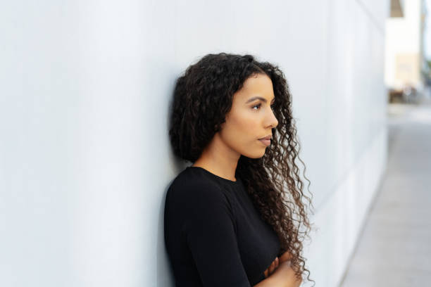 istock Troubled young woman standing leaning on a wall 1248690794
