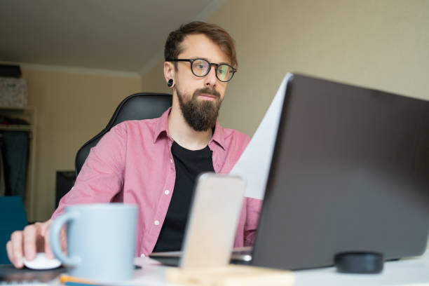 istock Bearded young man in eyeglasses working at home 1248693636
