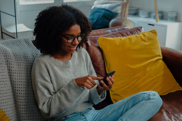istock Beautiful lady scrolling through smartphone on the couch at home 1248693975
