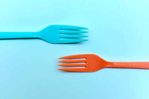 Two brightly colored forks facing towards each other on a ktchen table in retro style