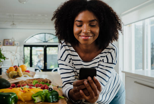 istock Young female browsing recipes on smartphone and smiling while in the kitchen, portrait 1248697352
